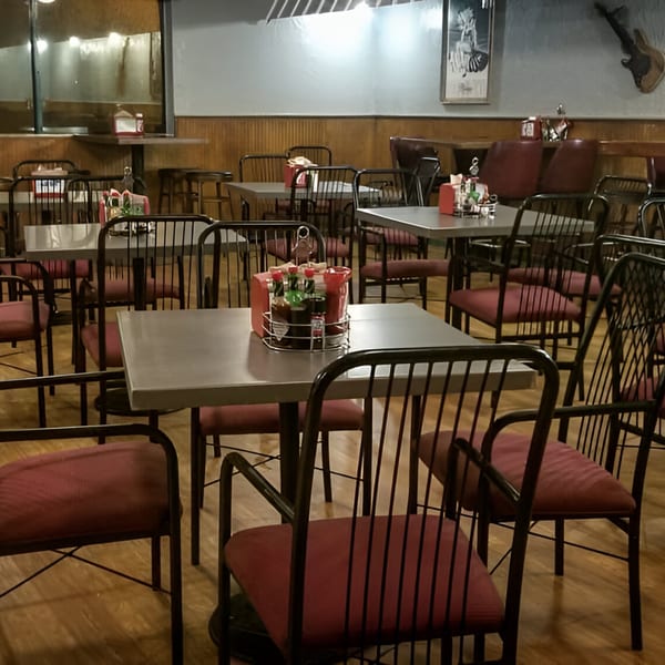 Interior of Nice N Easy Oyster Bar & Grille with empty tables, red chairs, and wood paneling.