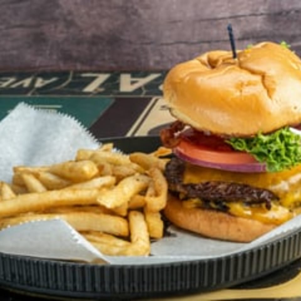 A cheeseburger with bacon, lettuce, tomato, and onion, served with a side of golden fries.
